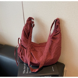 Detail of red checkered canvas hobo bag showing adjustable strap and side drawstring bow