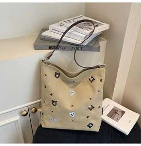 Close-up of cat embroidery and brown leather strap on a beige canvas tote bag