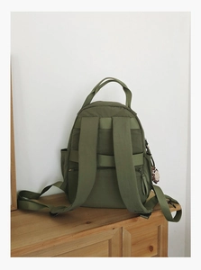 Detail view of the deep olive nylon backpack featuring side pockets and back safety zipper