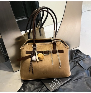 Detail of suede tote bag with leather straps, gold buckle and sports theme charms