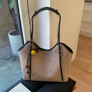 Detail of vintage taupe tote bag with tassel charm and adjustable black shoulder strap