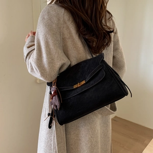 Detail showing vintage black suede crossbody bag with gold twist lock and bear charm