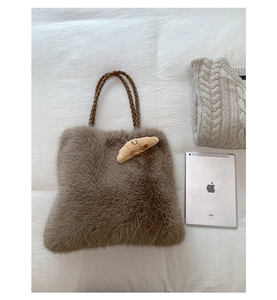 Detail view of fuzzy tote bag with braided handles and cute croissant charm accessory