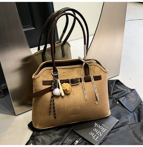 Detail of suede tote bag with leather straps and decorative baseball charm accessories