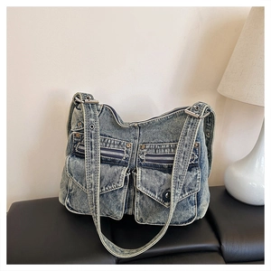 Détail d'un sac cabas vintage en denim délavé avec poches multiples et zips métalliques
