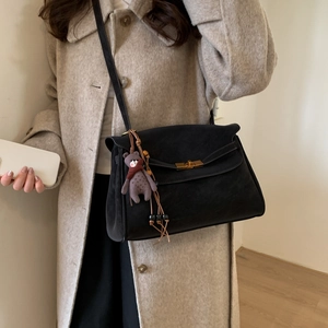 Close-up of black suede crossbody bag with gold twist lock and cute bear charm