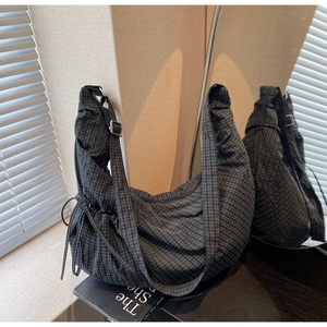 Detail of checkered canvas bag featuring drawstring pleats and adjustable strap buckle