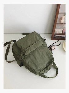 Close-up of deep olive green waterproof nylon backpack with front zipper pocket detail