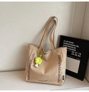 Detail of canvas tote bag featuring repeated Life text and yellow flower charm