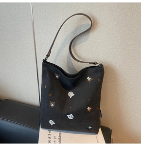 Detailed close-up of embroidered animal motifs on a black large capacity canvas tote bag