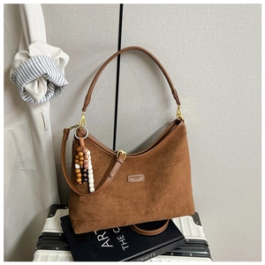 Details einer braunen Wildleder-Tragetasche mit Perlenanhänger und Vintage-Lederetikett
