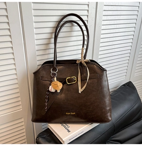 Detail of dark coffee suede tote bag with golden buckle and stylish scarf hanging on handle