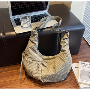 Detailed view of checkered canvas dumpling bag with gathered design and wide strap