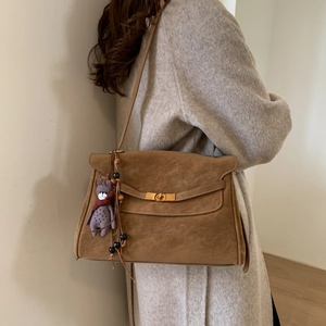 Detail of vintage brown shoulder bag with golden clasp and cute bear charm pendant