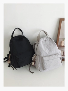 Detail view of black and grey nylon backpacks with cute owl plush keychain charms