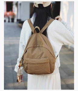 Detail view of khaki minimalist nylon backpack with side beaded keychain accessory