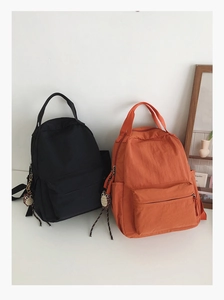 Detailed view of high-capacity nylon backpacks in black and orange with owl charms