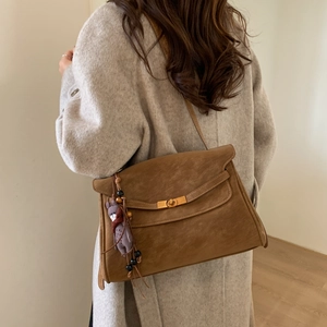 Close-up of a vintage brown crossbody bag with a gold lock and cute plush pendant