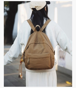 Outdoor shot showing back view of khaki nylon backpack with boho tassel detail
