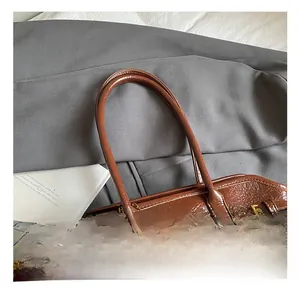 Detail view of brown glossy oil wax leather tote with golden buckles and chain