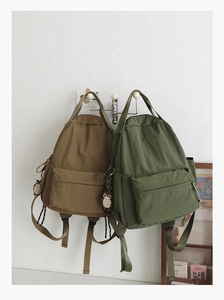 Detail view of khaki and olive nylon backpacks with large pockets and owl charms