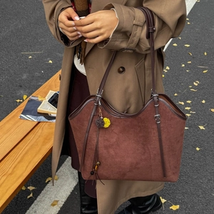 Detail of vintage dark brown suede tote bag with fringe charm on a stylish leather strap
