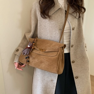 Detail of vintage brown suede crossbody bag with gold lock and tassel charm on wool coat