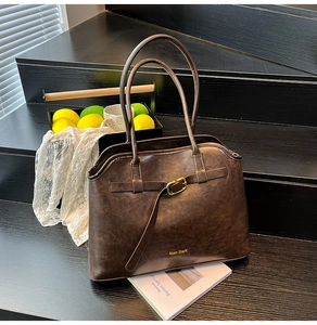 Close-up of deep brown suede tote bag with golden metal buckle and brand engraving