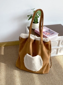 Close-up of caramel suede tote with faux shearling heart pocket and drawstring detail