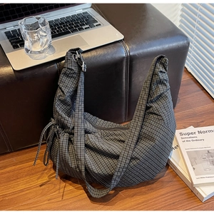 Detail of checkered canvas hobo bag with adjustable side drawstrings and smooth zipper top
