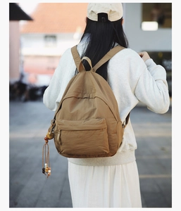 Detail of khaki lightweight nylon backpack with beaded charm in casual outdoor setting