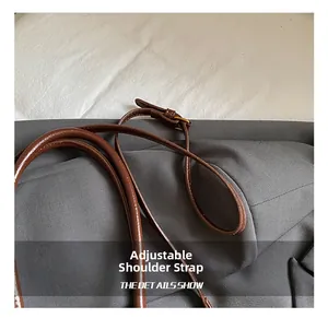 Detail view of adjustable leather shoulder strap with golden buckle on a tote bag