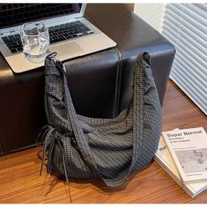 Detailed view of black and white checkered hobo bag with drawstring and wide strap