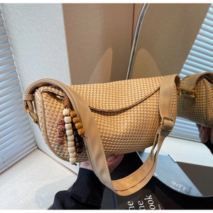 Detail of woven straw handbag featuring vintage wooden bead charms and brown leather strap