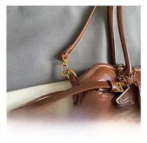 Detail showing dark brown oil wax leather tote bag with vintage gold metal hook and chain