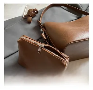 Close-up of brown PU leather bucket bag set with silver zipper and textured finish