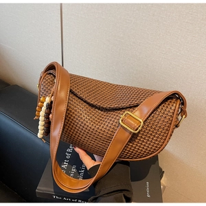 Detail of woven crescent bag with brown checkered pattern and wooden bead pendant accessory