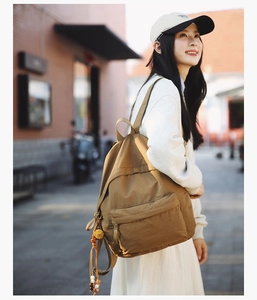 Close-up of brown nylon backpack with bohemian beaded tassel charms and front pocket