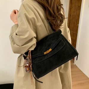 Detail of black matte suede shoulder bag with gold clasp and tassel charm