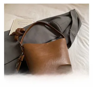 Detailed close-up of brown vintage leather bucket bag texture on a gray suit jacket