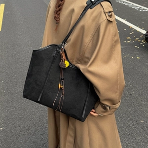 Street style view of a black suede tote bag with vintage wooden beads and tassel charms