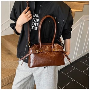 Detail of dark brown crinkled patent leather tote with gold buckle and brand logo