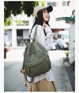 Olive green casual backpack worn by a model in an outdoor street setting