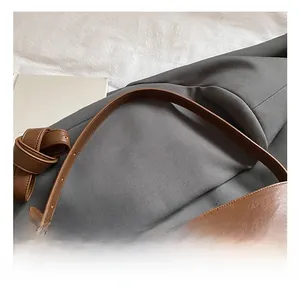 Detailed close-up of brown leather bucket bag with wide adjustable shoulder strap