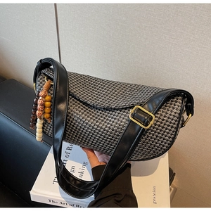 Close-up of woven dumpling bag with leather strap and colorful wooden bead charms
