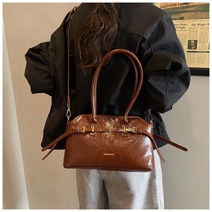 Brown tote bag detail with crinkled patent leather texture and metal buckle accents