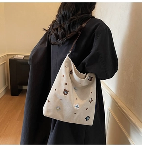 Detail of beige canvas tote bag with colorful animal embroidery and brown straps
