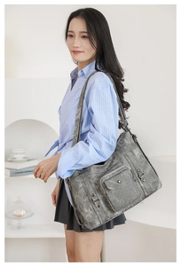 Close-up of grey vintage tote bag with functional pockets and metallic rivets details