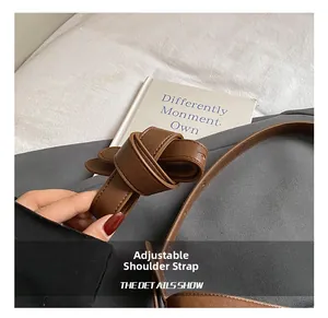 Detail of adjustable dark brown leather shoulder strap with neat stitching on handbag