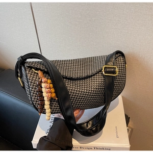 Detail of woven crescent bag with leather strap and decorative wood bead charm